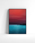 Minimal seascape wall art with a red sky, turquoise water and dark cliffs on the horizon.